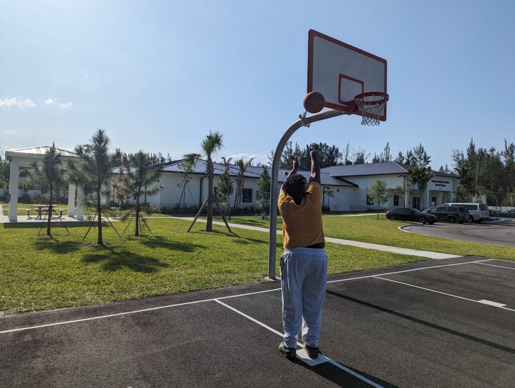 Outdoor basketball player shooting on court with clear sky.