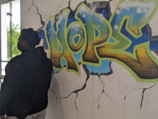 man standing next to graffiti