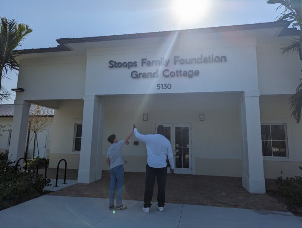 Two people high-fiving in front of Homesafe Grand Cottage entrance.