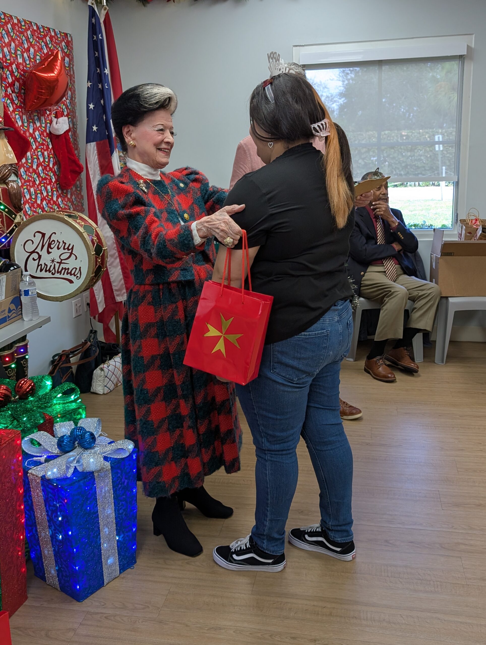 Woman receiving a Christmas gift from another woman at Homesafe event.